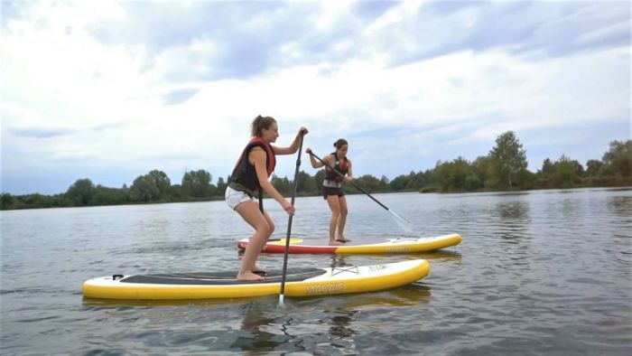 Auf diesem Bild sieht man einige junge Frauen beim Stand Up Paddeln auf dem Baggersee in Ertingen